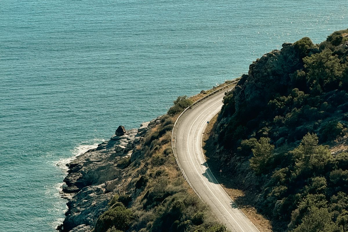 A winding coastal road curving around a headland above the turquoise sea near Antalya